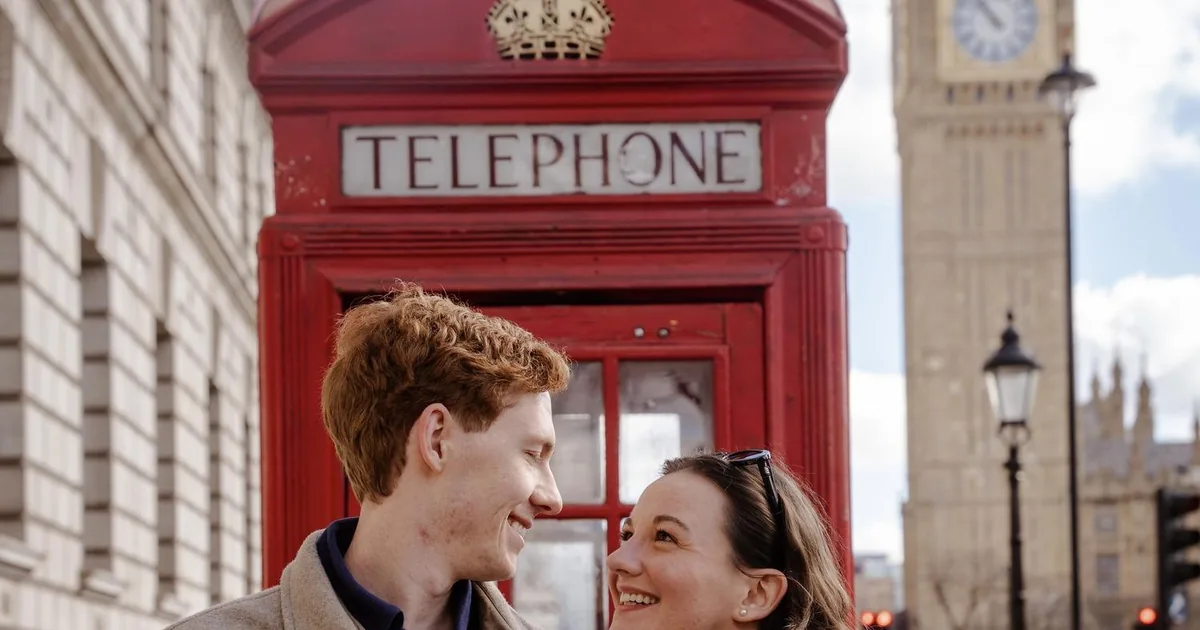 A couple laughing beside a red phone box with Big Ben behind them, on a London photoshoot