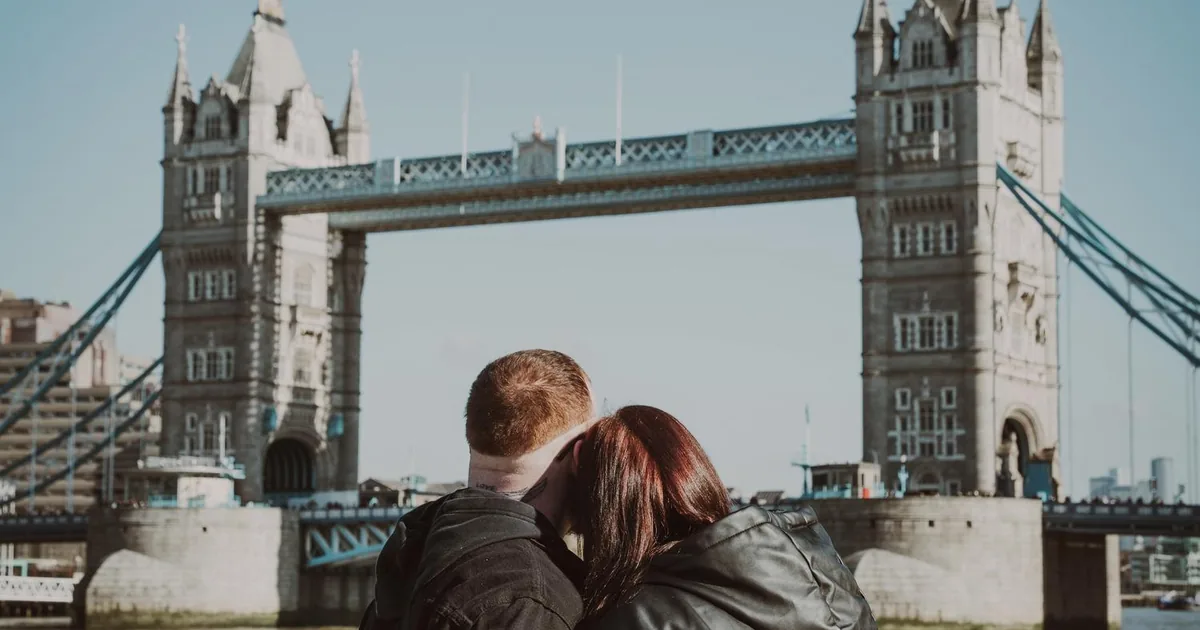 A couple embracing by the river with Tower Bridge behind them