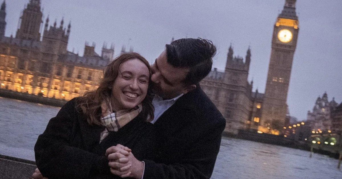 A couple embracing on the South Bank with the Houses of Parliament and Big Ben behind them at dusk