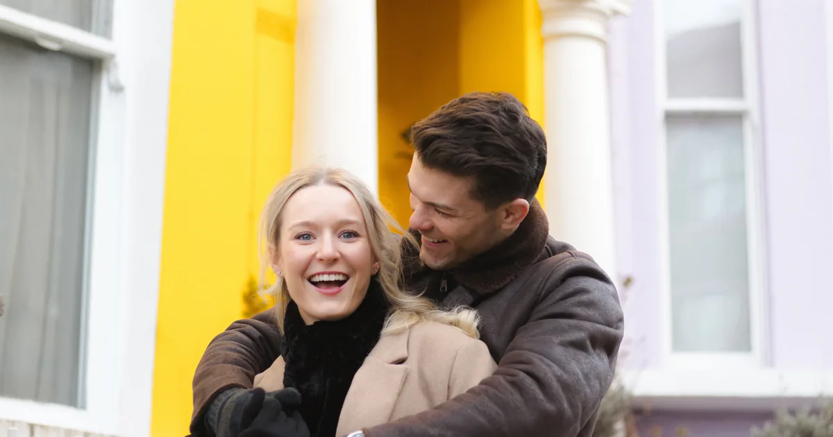 A couple laughing in front of a bright yellow house front in Notting Hill